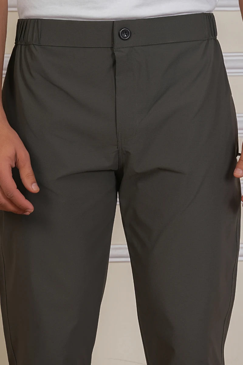 Dark gray pants with a button on a neutral background