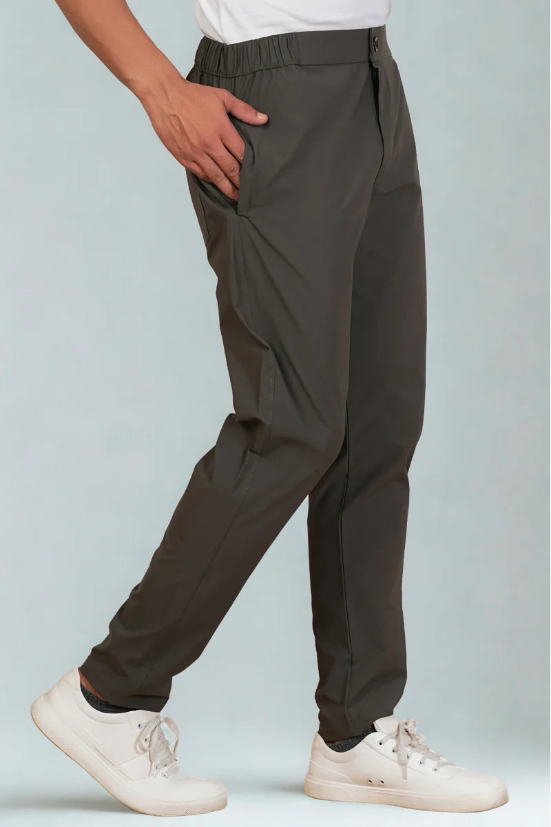 Person wearing dark gray pants and white sneakers on a light blue background