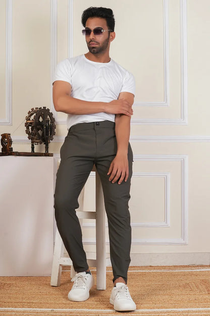 Man wearing a white t-shirt, gray pants, and white sneakers in an indoor setting.