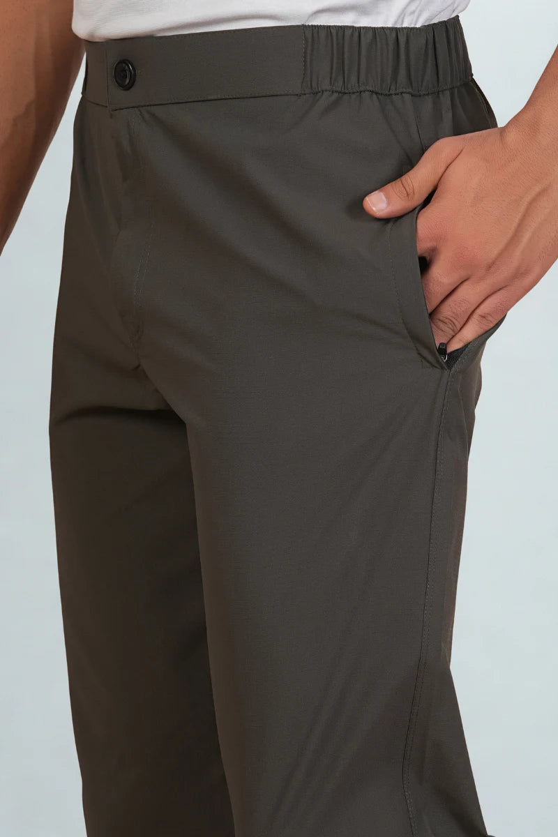 Dark gray pants worn by a person on a light blue background